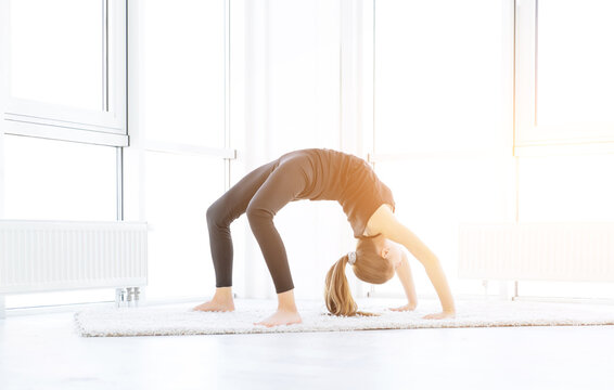 Flexible girl performing bridge exercise indoors