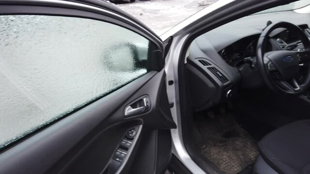 Europe, Ukraine, Kiev - December 2020: Opening of the icy car. The car does not open due to ice. Warming up the car during icy conditions. The car door is frozen and won't open.