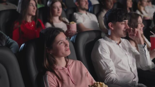 Young audience watching funny movie in cinema.