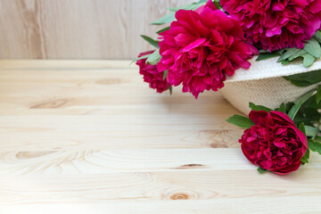 pink red peonies in wicker hat on wooden background