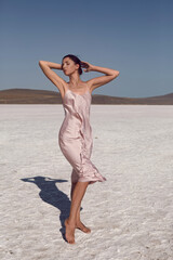 Fototapeta na wymiar woman on a dried up salt lake in a pink dress in the Crimea
