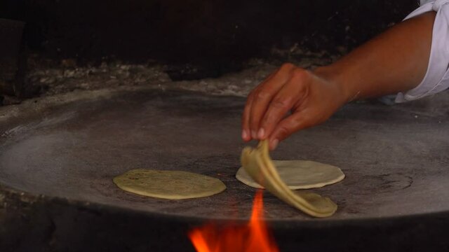Making tortillas in comal with hands. Flipping tortillas in comal.