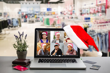 Computer in cozy room with hanging red hat and with Santa Claus on screen wishing Merry Christmas and Happy New Year online - Powered by Adobe