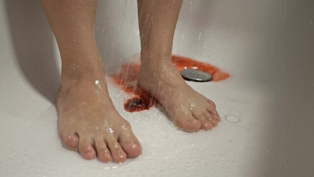 Women's feet in the shower. The water washes away the blood. Spontaneous miscarriage in the early stages.