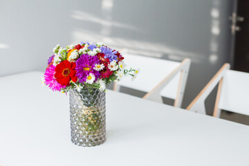 A bouquet of multi-colored flowers on a white table