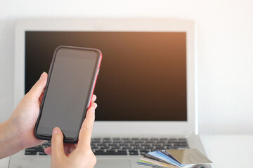 women hand holding smart-phone with laptop and credit cards,online shopping concept.