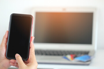 women hand holding smart-phone with laptop and credit cards,online shopping concept.