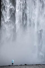 Woman admiring Skogafoss waterfall in Iceland