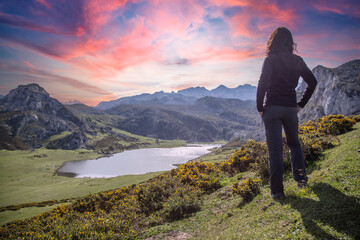 A young woman looking at the beautiful Covadonga lake in Asturias in a beautiful spring sunset,...