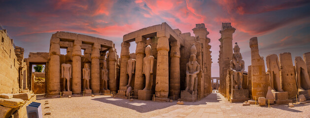 Sculptures of ancient Egyptian pharaohs and drawings on the columns of the Luxor Temple in the evening. Egypt - obrazy, fototapety, plakaty