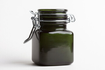 A small scented candle in a green glass candlestick with a tight lid. Paraffin and vegetable wax. Isolated on white background