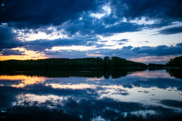 the sunset is reflected in the lake. beautiful sunset. forest in the distance.
