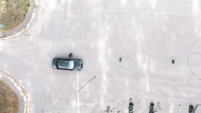 practical driving test. student on a black car bypasses obstacles. driver flunked exams by hitting tires. aerial view. driving training area, driving course. Driving lessons training. top shot