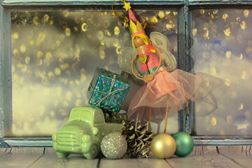 A magical fairy in a pink puffy dress with gifts for the new year. Christmas tree toys, a cone and...
