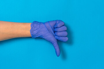 Hand in medical glove shows gesture thumb down or dislike