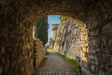 Obraz premium Big tower in the Medieval castle of the city Brescia on a sunny clear day against a bright blue sky. Part of Brescia castle on the hill Cidneo. view from the arch. Castello di Brescia, Lombardy, Italy