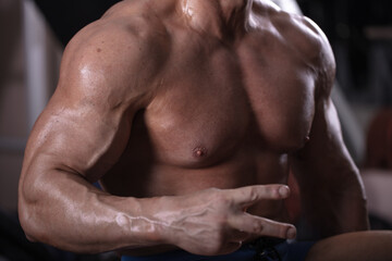 Fototapeta na wymiar Torso of a strong man who is engaged in bodybuilding on simulators. Athlete's torso close up