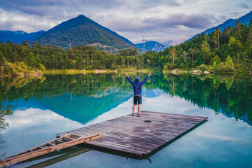 Happy man at the wooden pier of Alpsee lake . Human strength, psychology concept