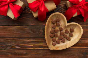 Chocolates hearts and present boxes on brown wooden background. Top view. Copy space. Valentines day celebration concept