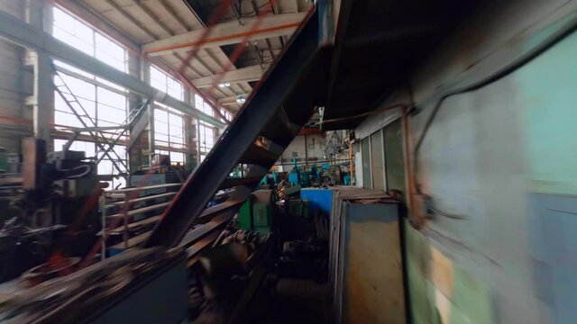 Aerial, FPV, drone shot flying low, through and over machines inside a old car manufactory hall
