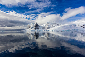 Crystal clear sky breaks open over iceburgs and snowy mountains in Anarctica
