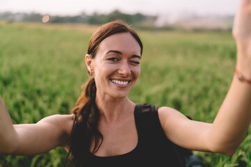 Positive woman smiling and winking while making selfie