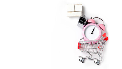 alarm clock in a pink plastic case and black hands in a metal shopping cart with tally click counter on a white background selective focus isolated