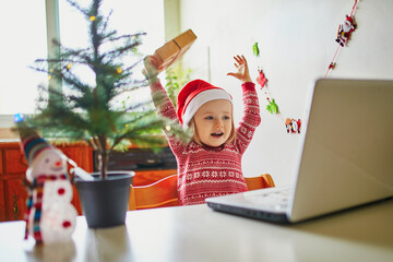 Kid using computer to communicate with friends or elderly relatives on Christmas or New Year