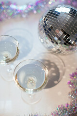 Glass of champagne in a coupe with disco ball and sparkles. New Year party, birthday, girls day or other celebration event