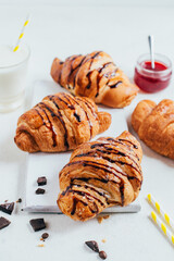 croissants with chocolate filling and strawberry jam on a white table close-up