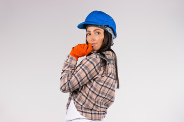 A woman mechanic in a hard hat holds a wrench on a white background looking at the camera. Side space for advertisment