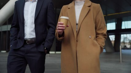 Mixed race businessman and Caucasian woman colleagues walking through street drinking coffee before business meeting