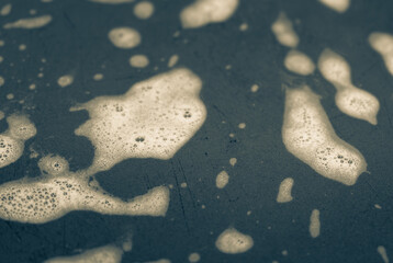 Abstract background with white foam on a colored surface in out-of-focus. Selective focus on cleaning foam.