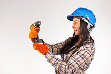  A woman builder in a hard hat on a white background with a drill in her hands. Combat gender...