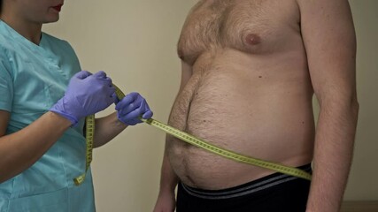 Doctor measures the abdominal circumference of an overweight patient. Man himself is dissatisfied with his appearance.