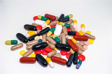 Variety of colorful medical pills spread on white surface large depth of field isolated on white