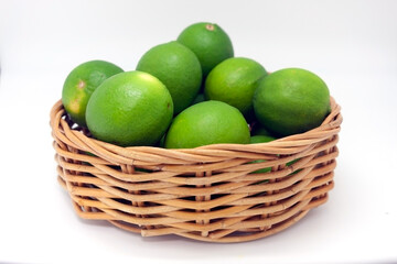 Basket with green limes isolated on white background
