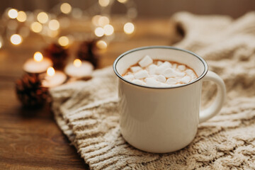 Delicious hot chocolate or cocoa drink with marshmallow candle lights and garlands in the background. Winter time. Christmas and new year concept