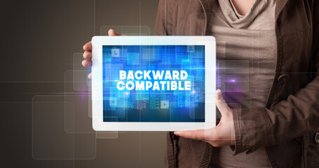 Young business person working on tablet and shows the inscription: BACKWARD COMPATIBLE