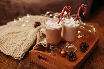 Delicious menu dessert hot winter drink chocolate or cocao with marshmallows and sweet cane for christmas and new year on wooden background with christmas balls and pine cones
