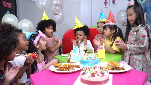 Group Diversity Kids Celebrating Clapping Hands And Singing Birthday Song To Friend. Girl Blowing Candles On Cake And Sharing To Friends In Party At Home. Multi Ethnic Children Having Fun Together