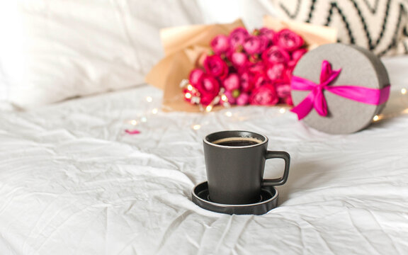 Coffee mug in bed on the background of a bouquet of flowers, a gift. Concept of Valentine's day, March 8. Copy space