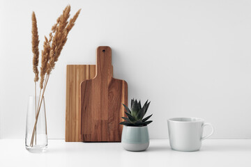 A mug, a potted houseplant, a clear vase and a wooden cutting board. Eco-friendly materials in the decor of the room, minimalism. Copy space, mock up.