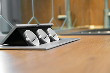 Three hidden sockets on a wooden kitchen countertop close-up, copy space