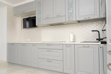 Fototapeta premium Beautiful classic kitchen in light gray, white tones in a new house.