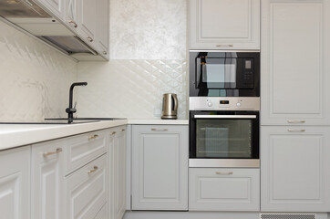 Beautiful classic kitchen in light gray, white tones in a new house.