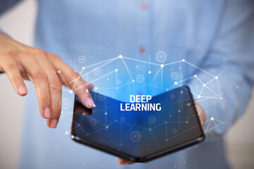 Businessman holding a foldable smartphone with DEEP LEARNING inscription, new technology concept