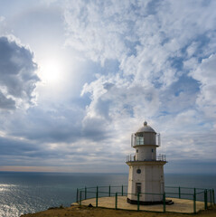 Fototapeta na wymiar lighthouse stay on marine cape under a dense cloudy sky