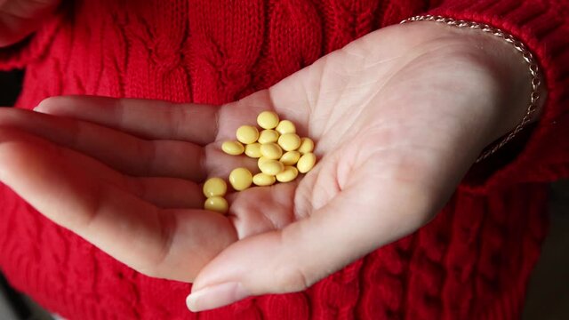 The girl pours yellow pills into the palm of her hand.