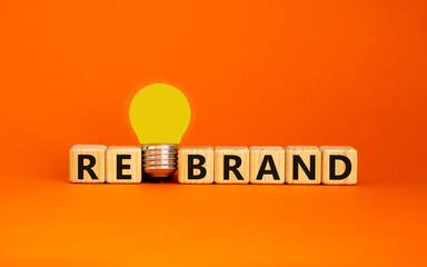 Rebrand symbol. Wooden cubes with word 'rebrand'. Yellow light bulb. Beautiful orange background. Business and rebrand concept. Copy space.